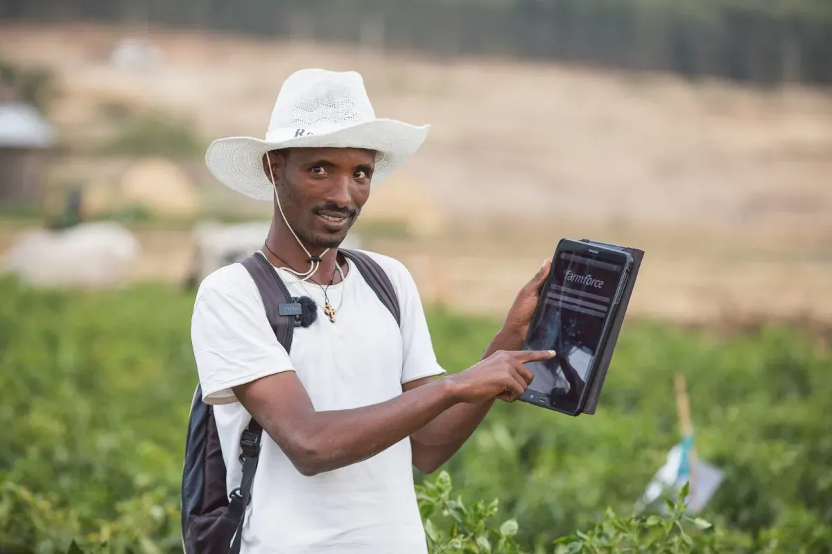 Image shows a farmer pointing to a tablet with traceability data for Farmforce