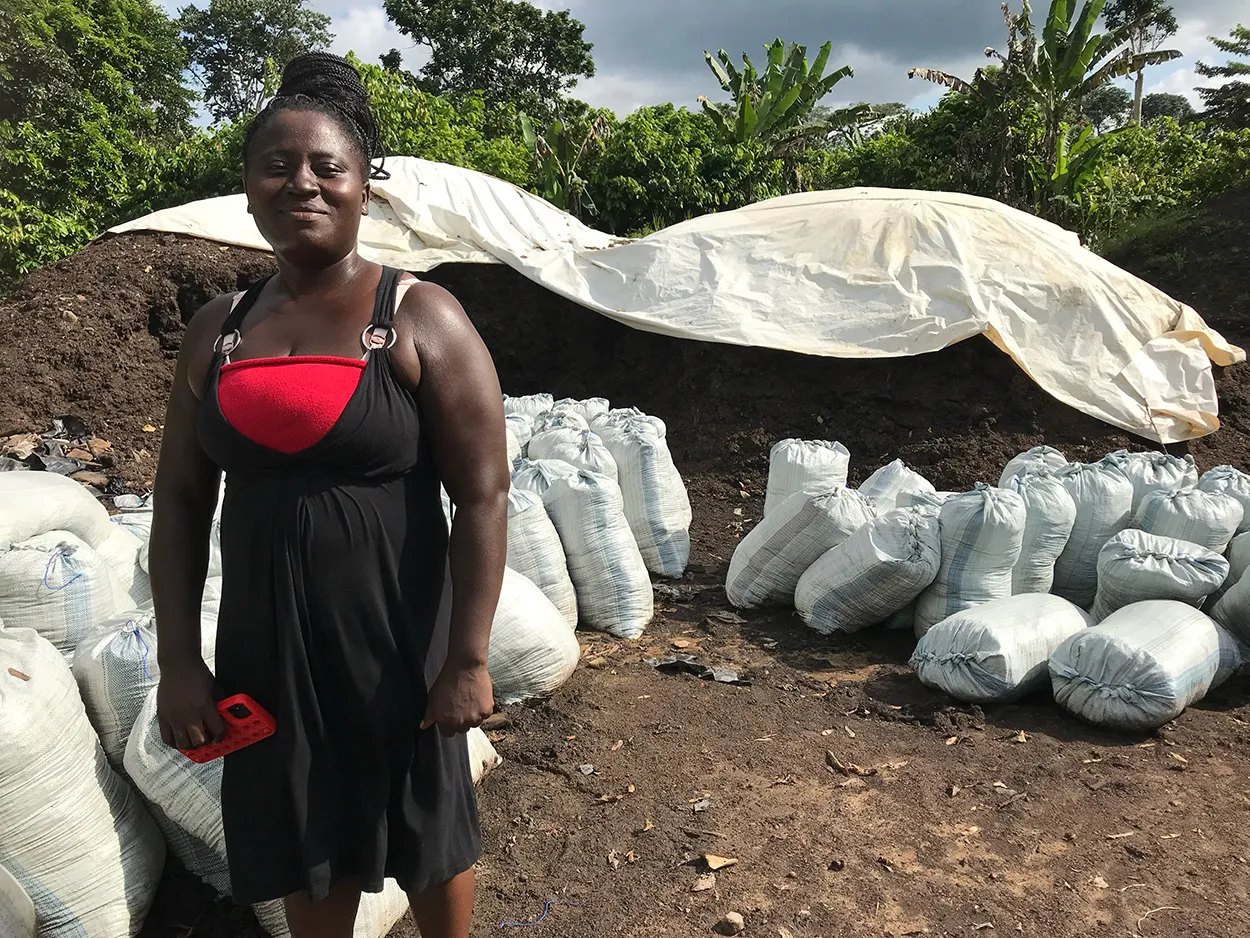 Image shows a female cocoa farmer bagging compost