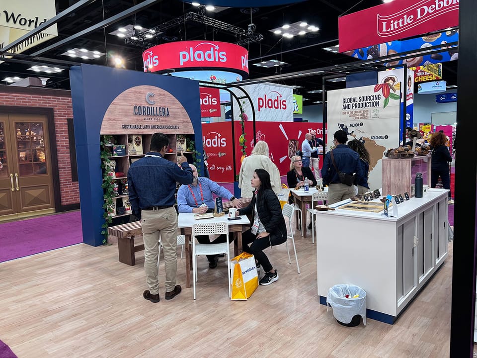 Image shows people at a confectionery booth at the Sweets & Snacks Expo.